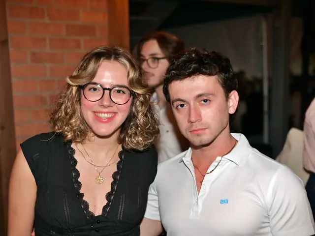 Couple smiling beside a brick wall at an evening event