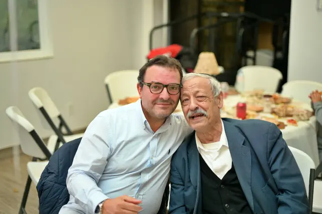 Two men laughing together at a catered table