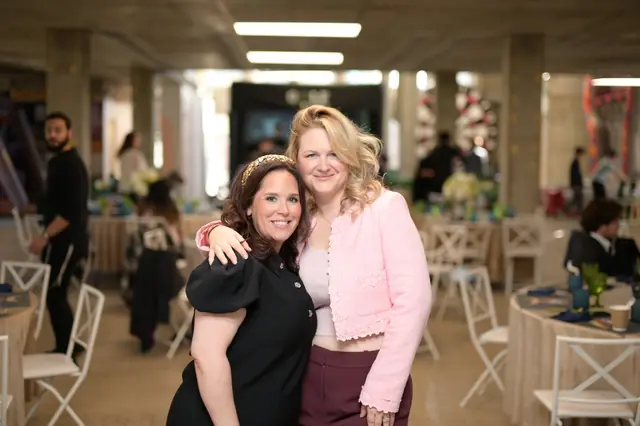Two women hugging in a modern event hall